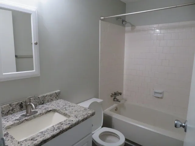 a bathroom with a granite countertop sink toilet and shower