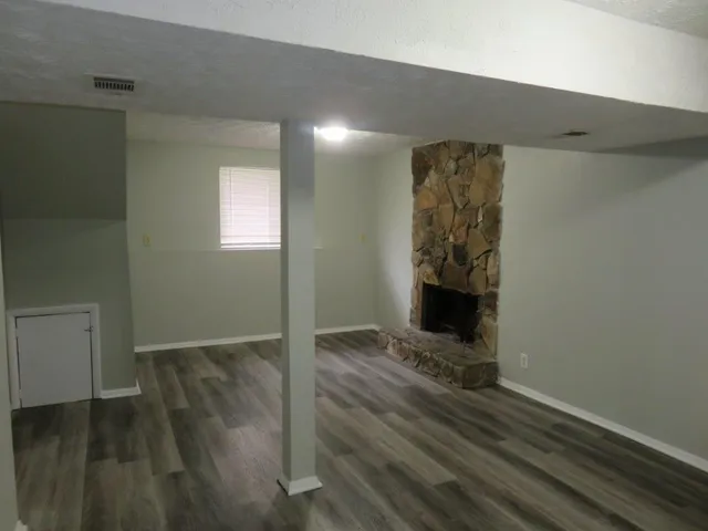 an empty room with wooden floor a fireplace and windows