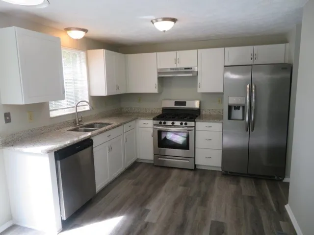 a kitchen with stainless steel appliances a refrigerator a sink a stove and cabinets
