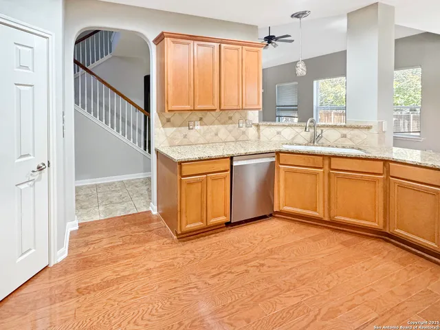 a kitchen with stainless steel appliances granite countertop a sink a stove and a wooden floors