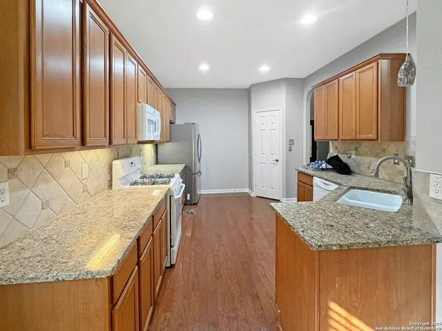 a kitchen with granite countertop a sink a stove and a wooden cabinets