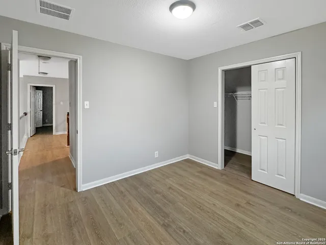an empty room with chandelier fan and windows