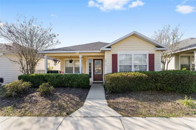 a view of a brick house next to a yard with potted plants