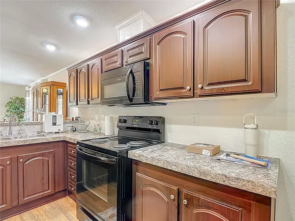 a kitchen with granite countertop stainless steel appliances sink stove and wooden floor