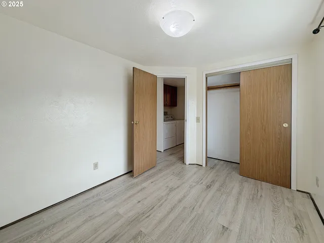 an empty room with wooden floor & closet area