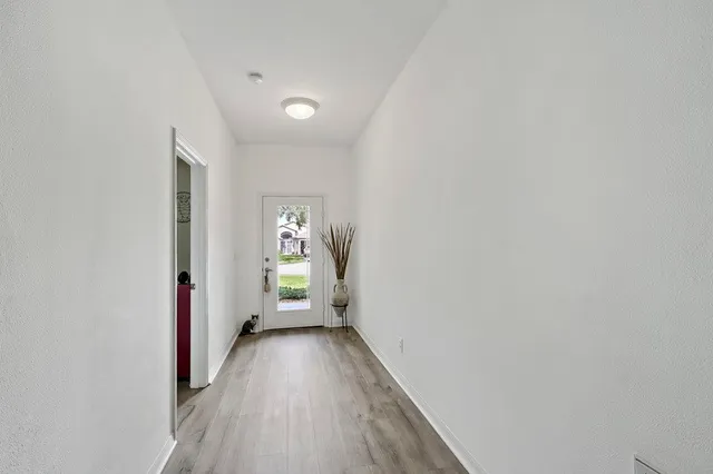 a view of a hallway with wooden floor and a bathroom