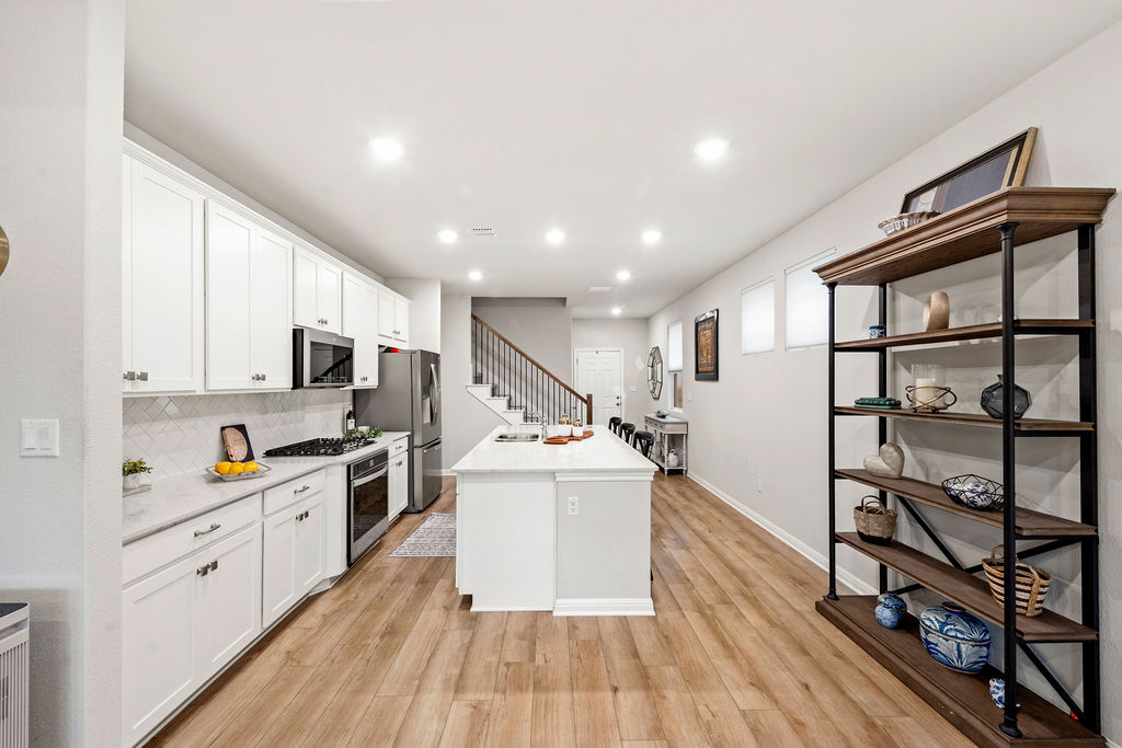 2417 Roosevelt Road Leander, TX 78641 - Photo 8 of 40 a kitchen with stainless steel appliances a stove top oven a sink a refrigerator and white cabinets with wooden floor