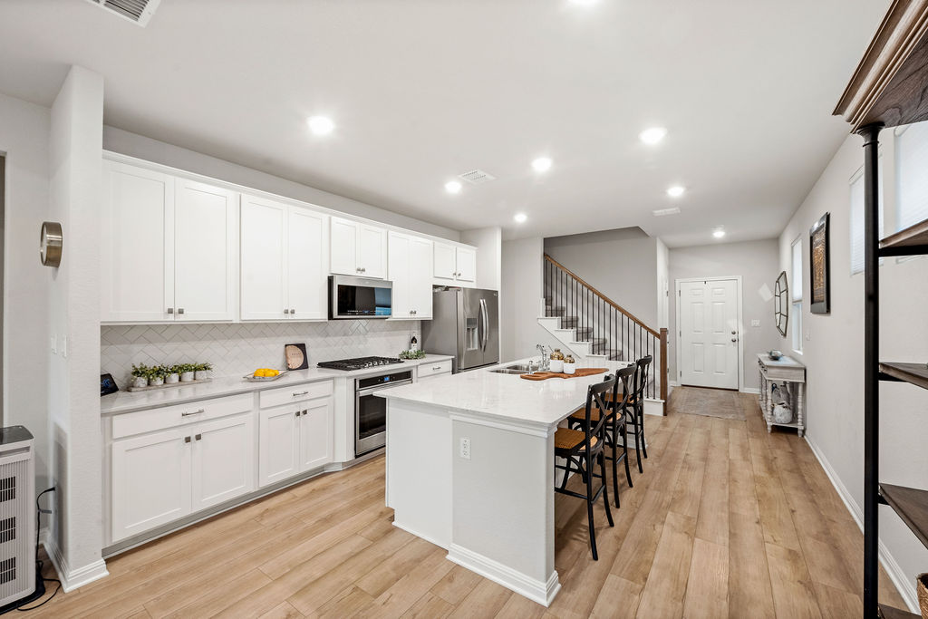 2417 Roosevelt Road Leander, TX 78641 - Photo 9 of 40 a kitchen with a sink a microwave a stove and white cabinets