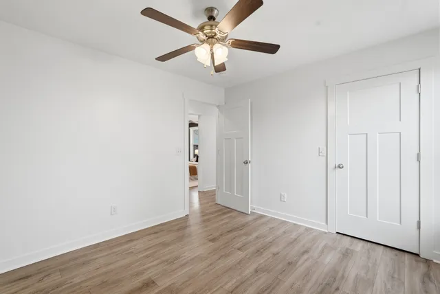 an empty room with wooden floor and ceiling fan