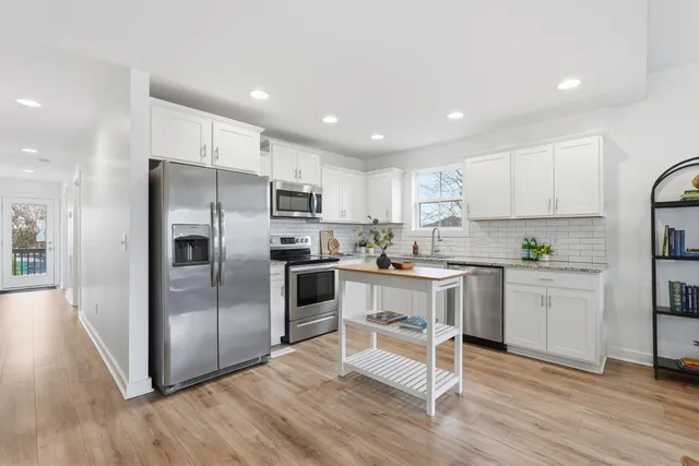 a kitchen with kitchen island white cabinets and stainless steel appliances