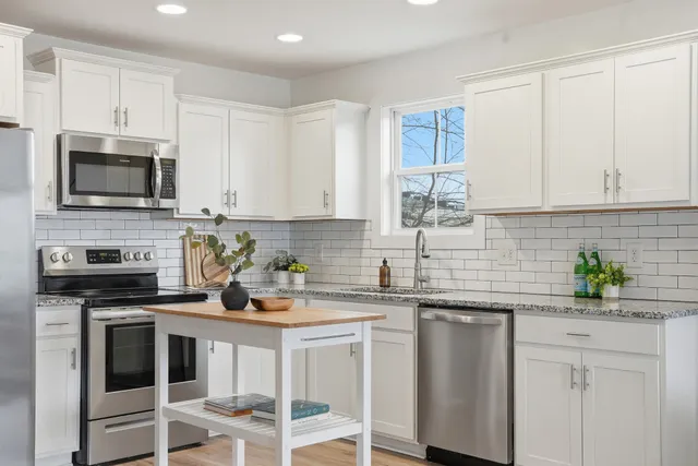 a kitchen with stainless steel appliances white cabinets sink and a microwave