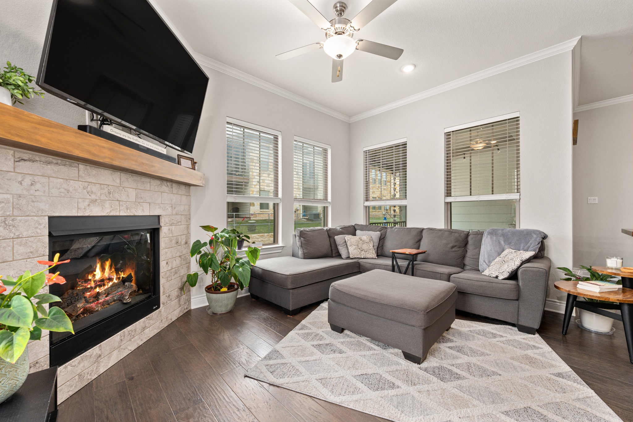 372 Adams Street Georgetown, TX 78628 - Photo 4 of 33 Spacious living area featuring hardwood floors, a tiled fireplace with a wooden mantel, and multiple windows providing natural light