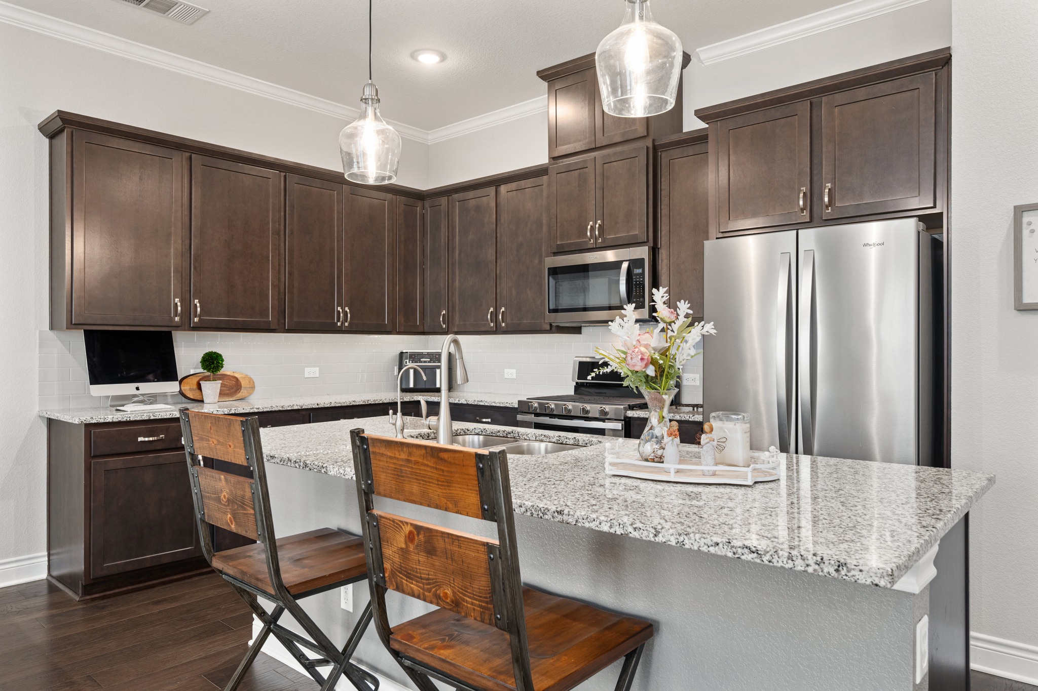 372 Adams Street Georgetown, TX 78628 - Photo 9 of 33 The kitchen features dark wood cabinetry, granite countertops, and stainless steel appliances, including a microwave and a refrigerator