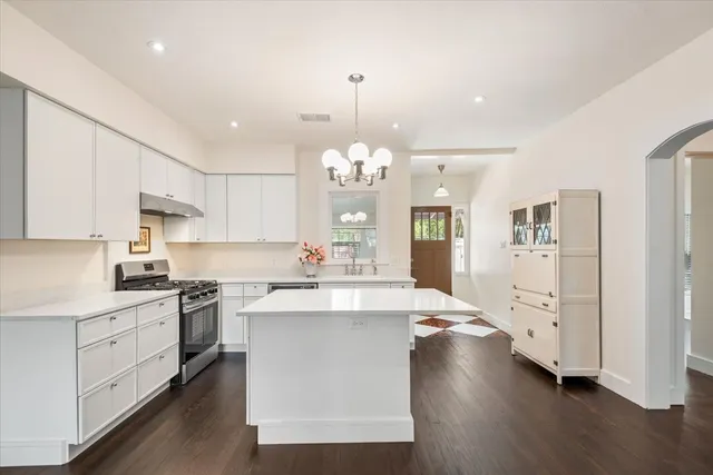 a large white kitchen with lots of counter space wooden floor and appliances