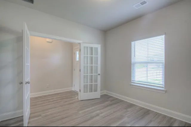 an empty room with wooden floor and windows