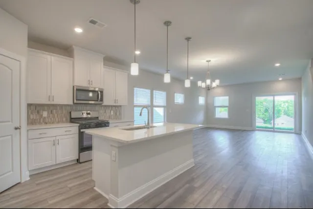 a open kitchen with kitchen island a sink dishwasher a dining table and chairs with wooden floor
