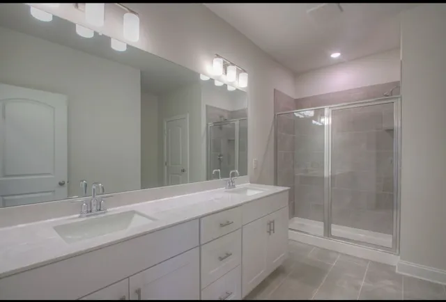 a bathroom with a double vanity sink mirror and shower