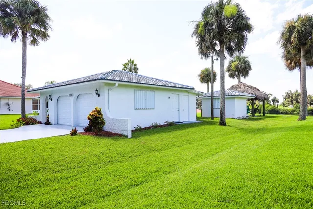 a view of a house with a yard and palm trees