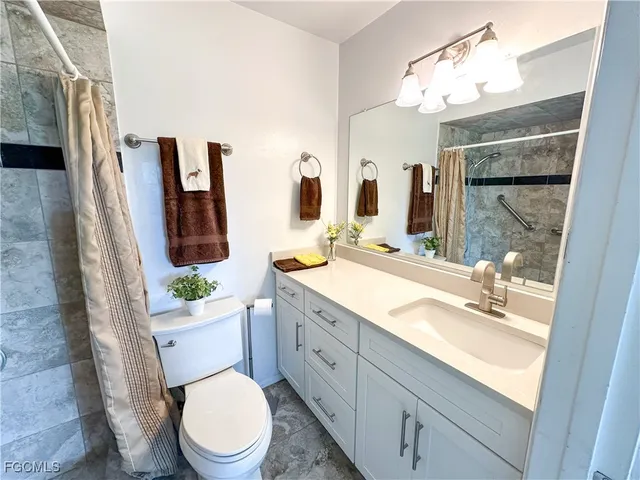 a bathroom with a granite countertop toilet sink and mirror
