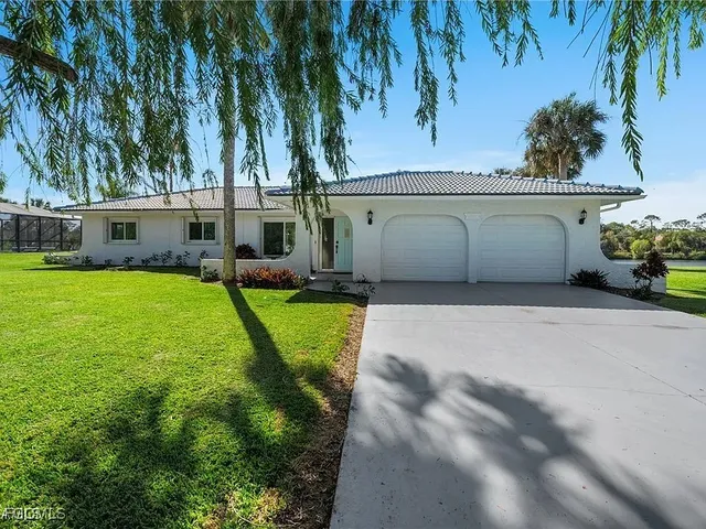 a view of a house with a yard and palm trees