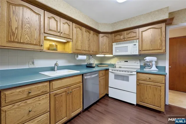 a kitchen with granite countertop wooden cabinets and white appliances