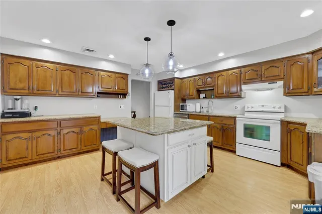 a kitchen with kitchen island granite countertop a sink counter top space appliances and cabinets