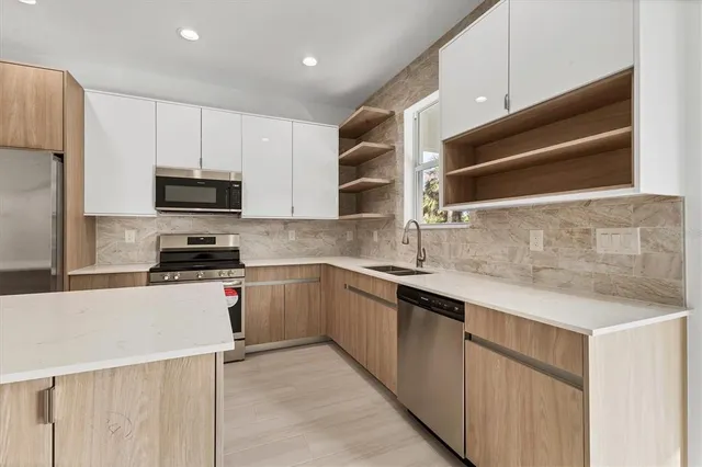 a kitchen with cabinets appliances a sink and a counter top space