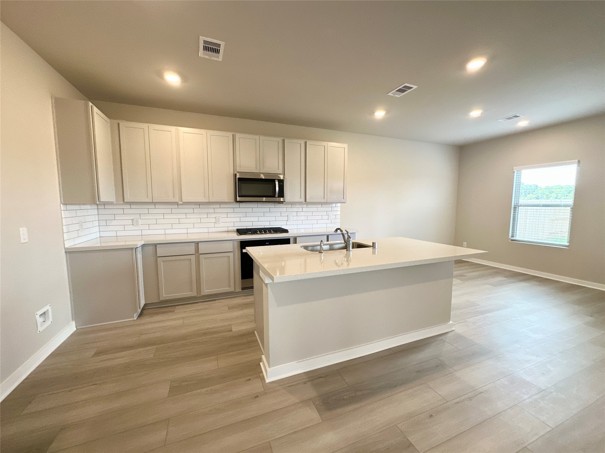 12176 Ridge Top Drive Conroe, TX 77304 - Photo 7 of 27 a large white kitchen with kitchen island a sink dishwasher a stove and a microwave oven with wooden floor