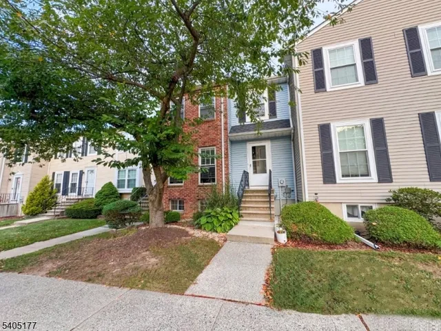 a front view of a house with garden and trees