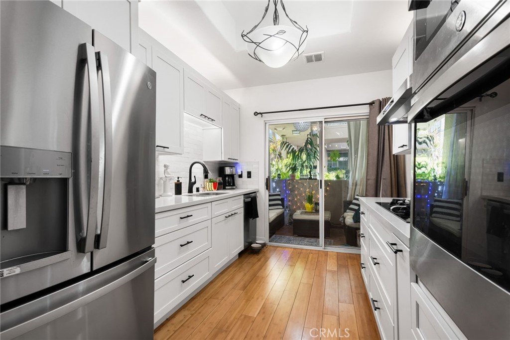 10626 Valley Spring Lane, Unit 103 Toluca Lake, CA 91602 - Photo 27 of 44 a kitchen with white cabinets and stainless steel appliances