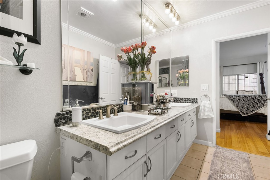 10626 Valley Spring Lane, Unit 103 Toluca Lake, CA 91602 - Photo 29 of 44 a bathroom with a granite countertop sink a large mirror and a toilet