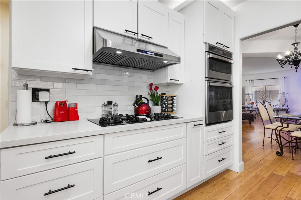 10626 Valley Spring Lane, Unit 103 Toluca Lake, CA 91602 - Photo 6 of 67 a kitchen with white cabinets and wooden floor