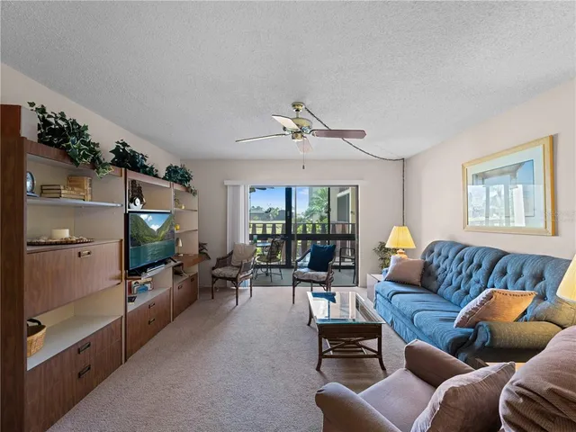 a living room with furniture a ceiling fan and a flat screen tv