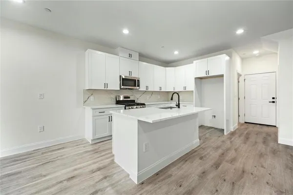 a kitchen with kitchen island a sink a stove a microwave and white cabinets