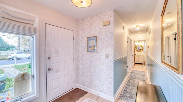 a view of a hallway with wooden floor and a bathroom
