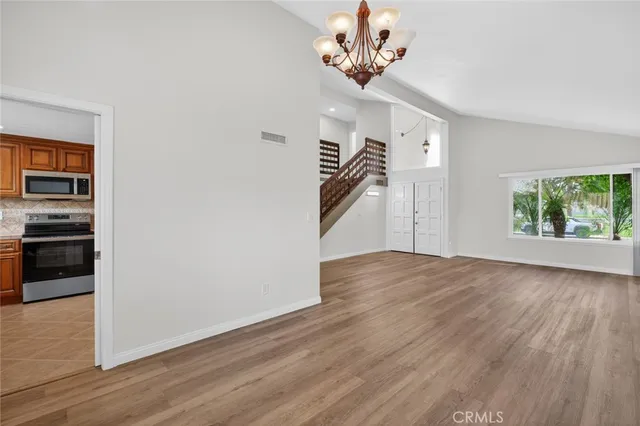 an empty room with wooden floor chandelier and windows