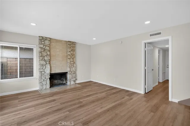 a view of empty room with wooden floor and fireplace