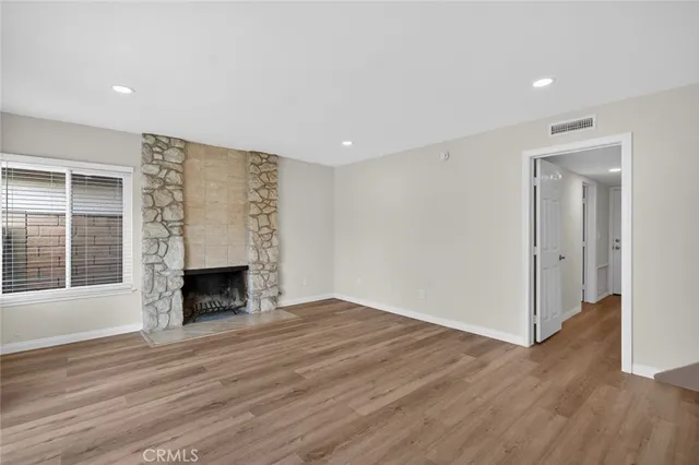 a view of empty room with wooden floor and fireplace
