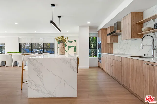 a view of a kitchen with kitchen island stainless steel appliances wooden floor and chairs