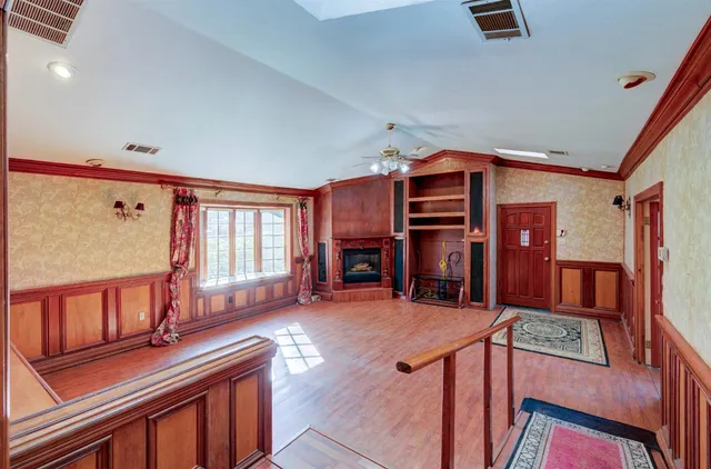 a view of an empty room with a window and hardwood floor
