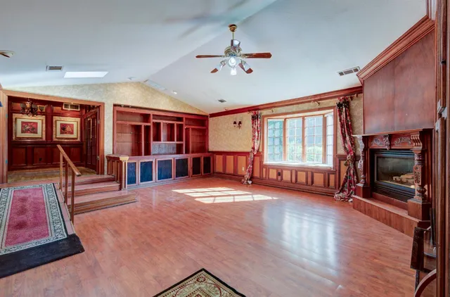 a view of an empty room with a fireplace chandelier fan and a fireplace