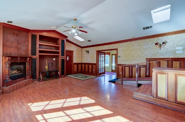 a view of a livingroom with a fireplace a chandelier and windows