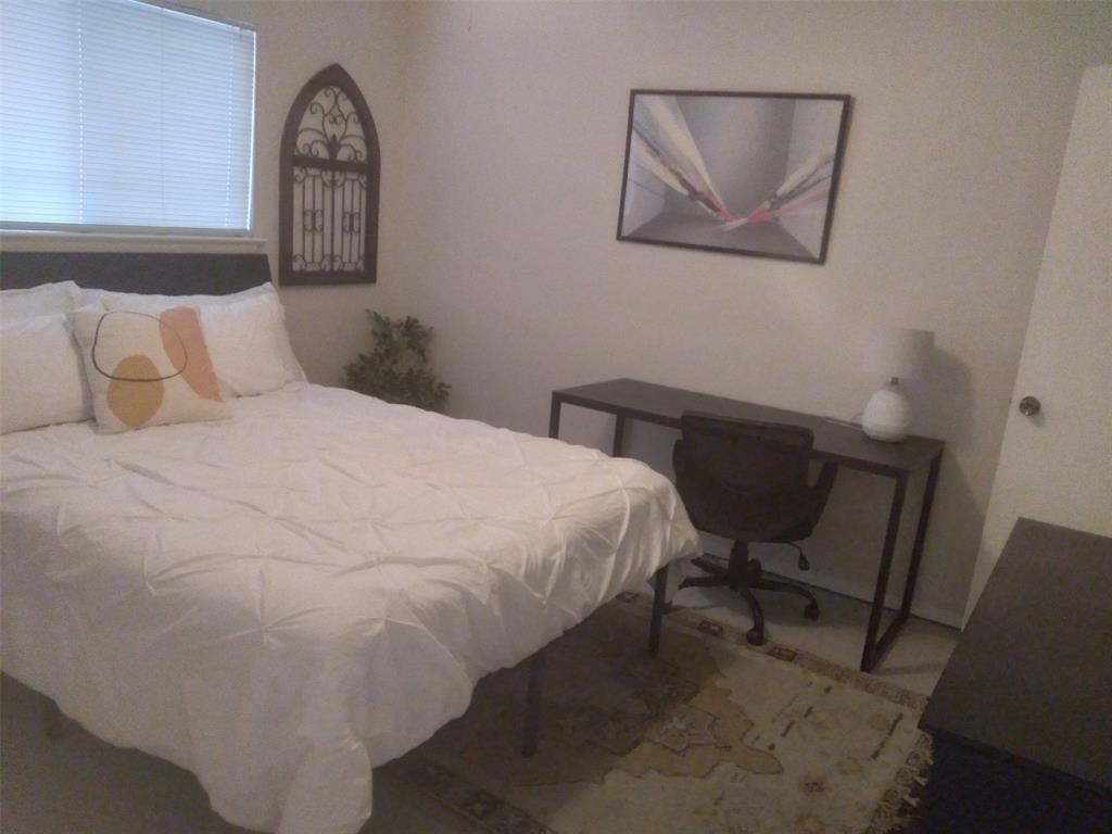 2714 McCart Avenue, Unit 2712 Fort Worth, TX 76110 - Photo 11 of 39 a bedroom with a bed and a chair