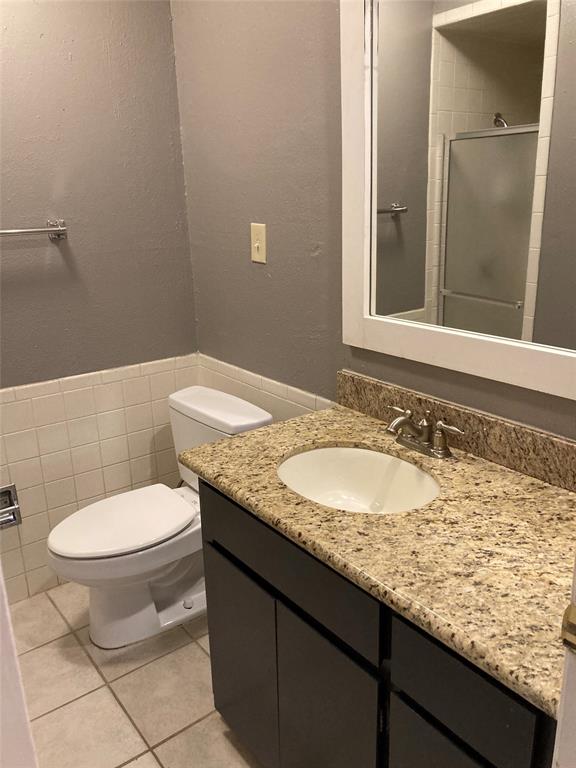 2714 McCart Avenue, Unit 2712 Fort Worth, TX 76110 - Photo 25 of 39 a bathroom with a granite countertop toilet a sink and a mirror