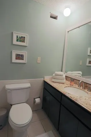 a bathroom with a granite countertop toilet a sink and a mirror