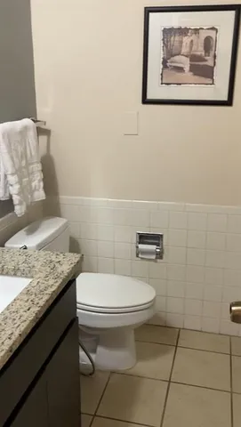 a bathroom with a granite countertop toilet and a sink