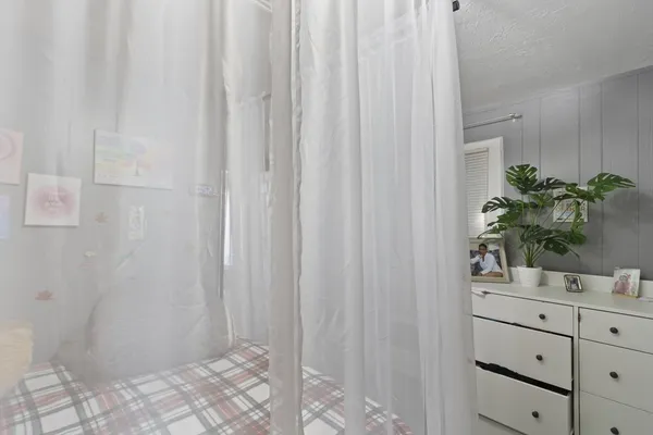 a bedroom with a bed and a flat tv screen on dresser