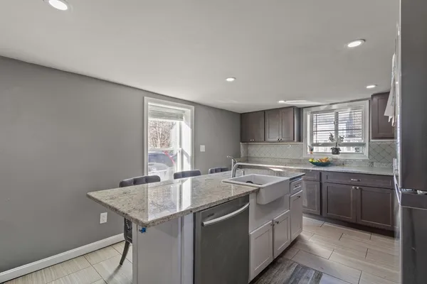a large kitchen with kitchen island a large window a sink a counter space and stainless steel appliances