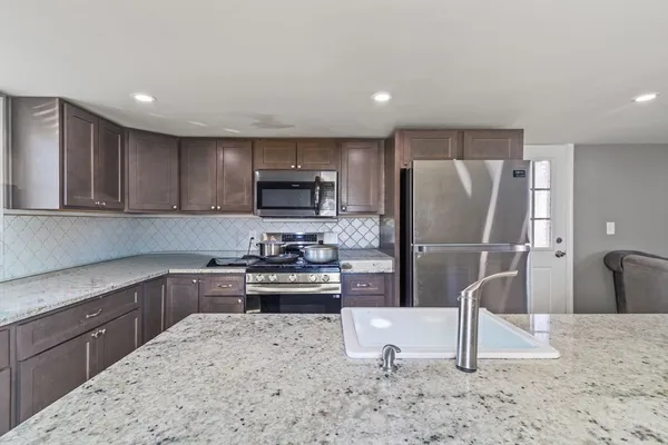 a kitchen with stainless steel appliances granite countertop a sink a refrigerator and a granite counter tops