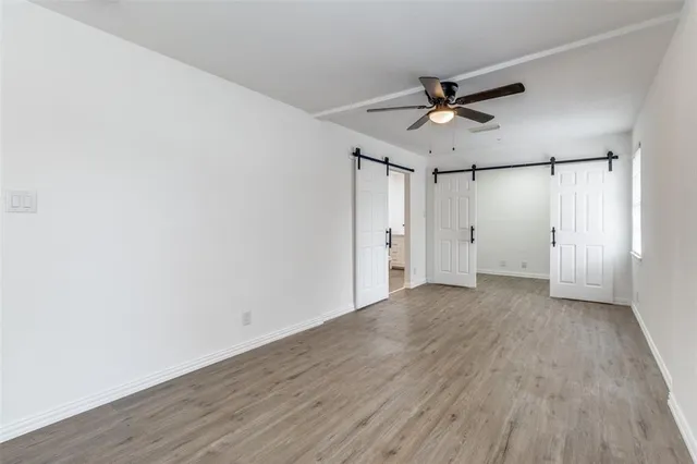 an empty room with wooden floor ceiling fan and windows